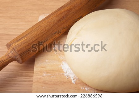 dough on a board and rolling pin with flour for sprinkling