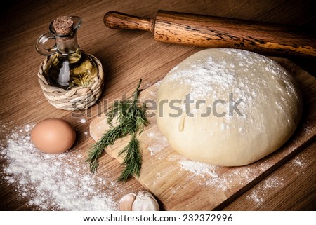 dough on a board with flour. olive oil, eggs, rolling pin, garlic