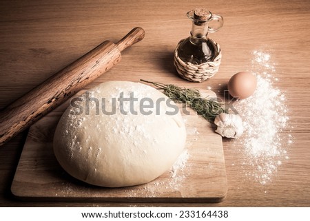 dough on a board with flour. olive oil, eggs, rolling pin, garlic and dill. Tinted.