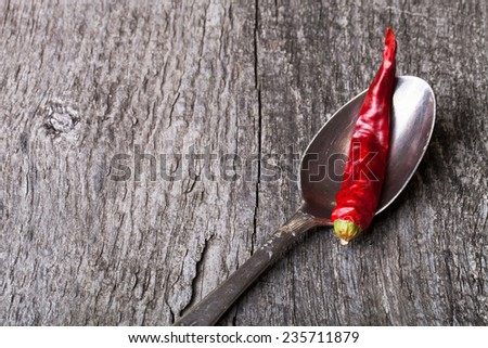 red hot chili peppers in German silver spoon on old wooden table