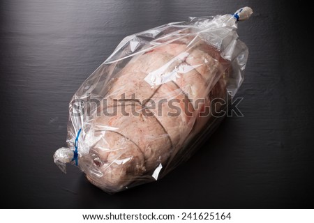 Raw meat with rope in the package on a black background.