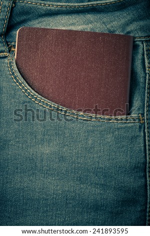 The pocket of jeans with document. Cloth background. Toned.