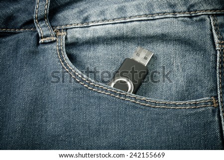 The pocket of jeans with flash card. Cloth background. Toned.