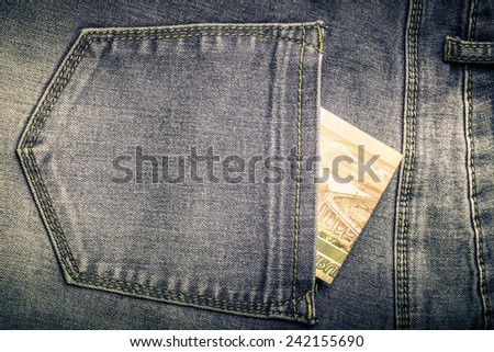 The pocket of jeans with money. Cloth background. Toned.
