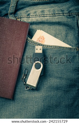 The pocket of jeans with document, money amd flash card. Cloth background. Toned.