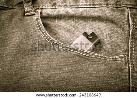 The pocket of jeans with lighter. Cloth background. Toned.