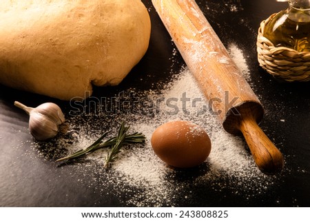 dough on a black board with flour. olive oil, eggs, rolling pin, garlic