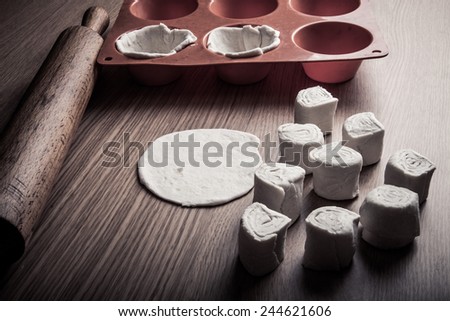 Form for pastry, rolling pin and pieces of dough on the wooden board. Toned.