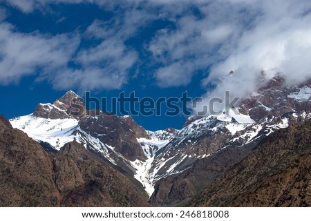 Clouds over the snow-covered tops of the rocks. Landscape.