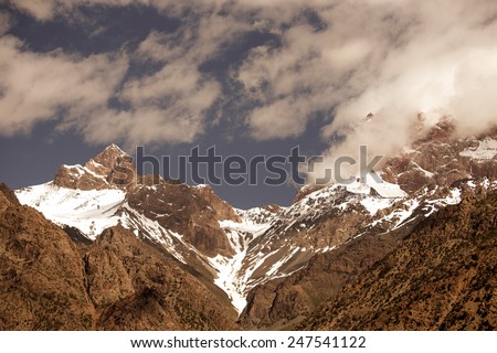 Clouds over the snow-covered tops of the rocks. Landscape. Toned.
