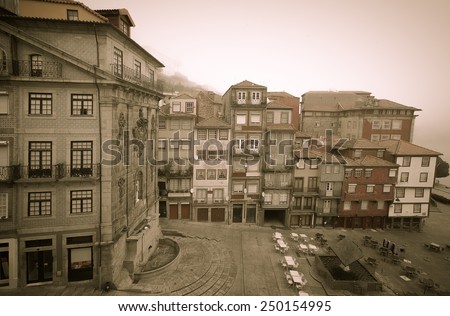 Old houses and an outdoor cafe on a misty river embankment. Portu. Toned.