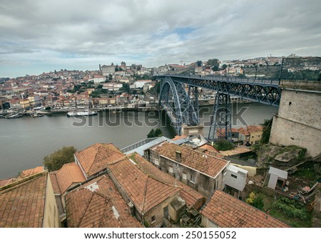 Red tiled roofs, metal bridge, old houses and the river Douro in Porto. Low clouds. Toned.