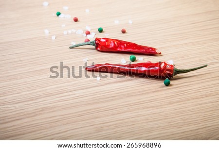 Red chili, sea salt and colorful bell pepper on a light wooden table.