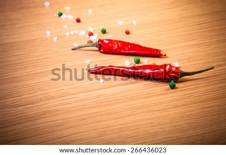Red chili, sea salt and colorful bell pepper on a light wooden table. Toned.
