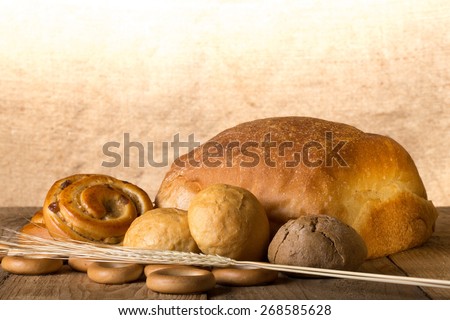 Bread assortment and wheat ears on an old wooden table.