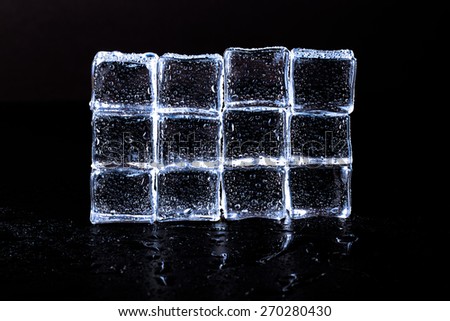 Wall of Ice cubes on black wet table. Selective focus. Toned.