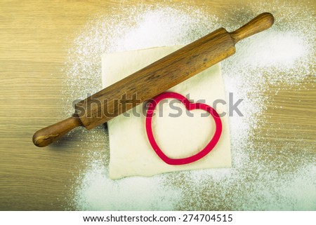 Set for home baking on a light wooden table with flour. Rolling pin, baking form, dough. Toned.