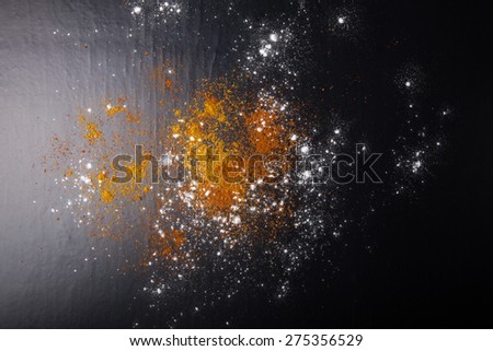 Red and yellow spices and flour on a black background. Selective focus. Culinary galaxy and planets.
