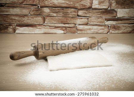 Set for home baking on a light wooden table with flour. Rolling pin and dough. Toned.