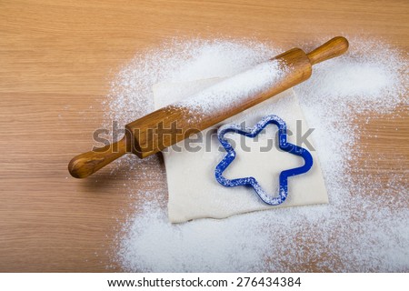 Set for home baking on a light wooden table with flour. Rolling pin, baking form, dough.