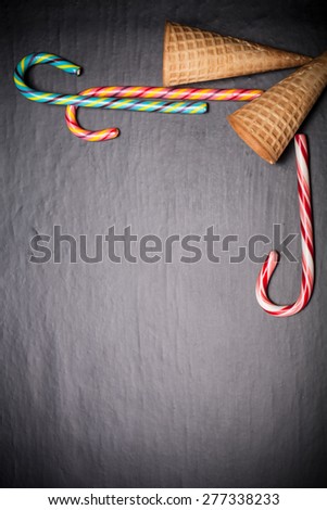 Candy sticks and waffle cones for ice cream on a black background. Space for text.