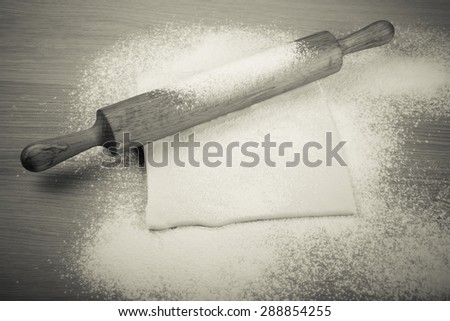 Dough and rolling pin on a light wooden table with flour. Toned.