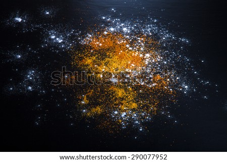 Red and yellow spices and flour on a black background. Selective focus. Culinary galaxy and planets.