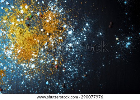 Yellow and red spices, sea salt and color pepper on a black background. Selective focus. Culinary galaxy and planets. Toned.