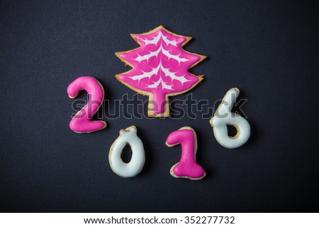 Gingerbread homemade cookies with icing on a black table or board for background. Figures 2016 New year theme. Toned.