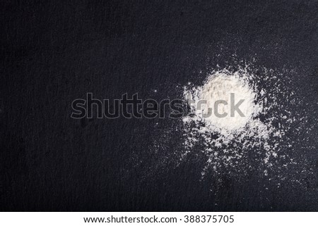 Flour spilling on color background of slate cutting board.
