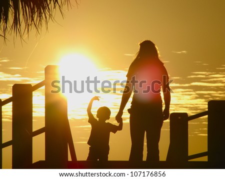 mother and son on bridge in sunset silhouette