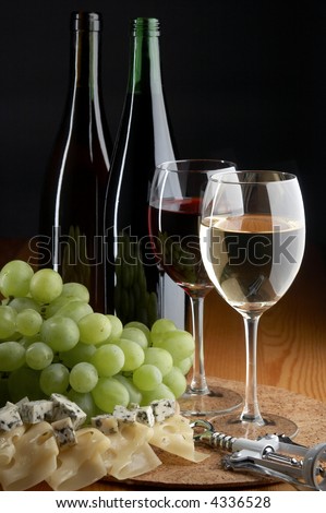 still life with grape, cheese, red and white wines on the black background