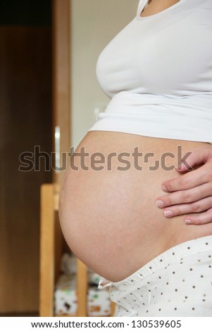 Pregnant woman hugging her bare pregnant tummy