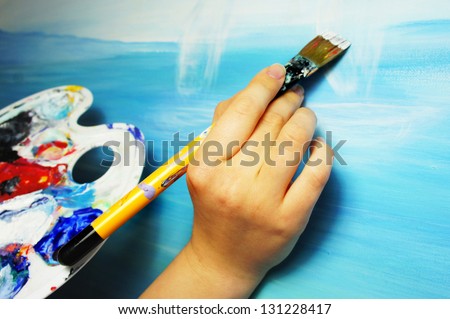 Artist hand with paintbrush painting the picture