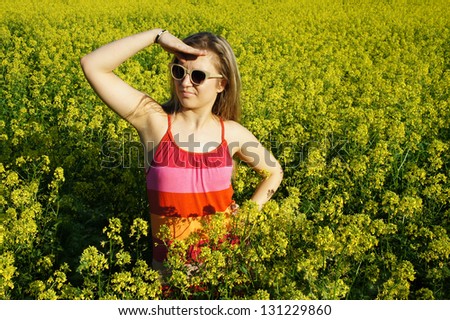 Young beautiful funny woman and field with beautiful yellow vivid flowers