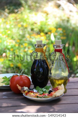 Piece of pizza in the summer garden table with olive oil and vinegar sauce
