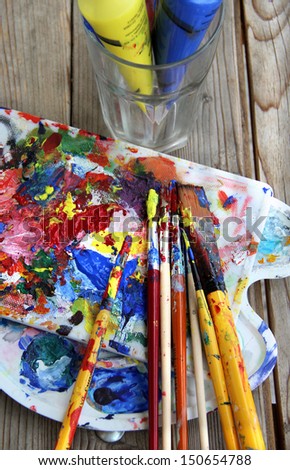 Art palette with a lot of paints and paintbrushes