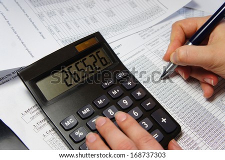 Calculator, pen and accounting document with a lot of numbers and woman hands