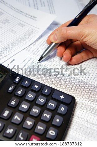 Calculator, pen and accounting document with a lot of numbers and woman hand