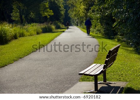Park bench and people on a bike path.