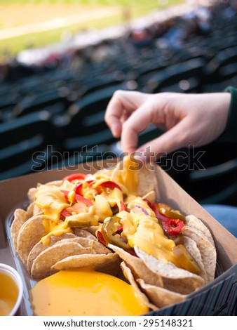 Sports Stadium Food - Person holding a tray of nachos with a female hand picking out a chip