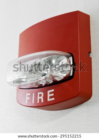 Red fire alarm with strobe light mounted on a wall as part of a fire protection system.