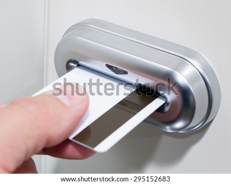 Person\'s hand inserting a magnetic stripe keycard into an electronic card key door lock