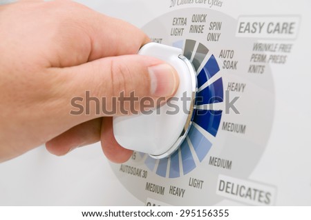Picture of hand turning the time dial on a top load washing machine