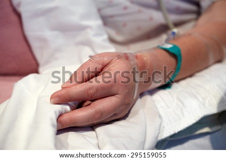 Hospital patient. Picture of a female patient\'s hand with an intravenous IV drip tube in a hospital bed.