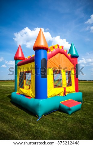 Children's bouncy house castle in a large open yard.