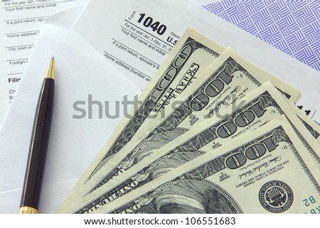 Tax papers in an envelope with 100 dollar bills