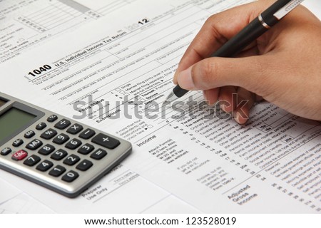 Person completing 1040 tax form with calculator
