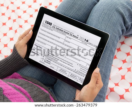 Woman  filing federal income tax over internet using form 1040 on mobile tablet computer and wireless technology