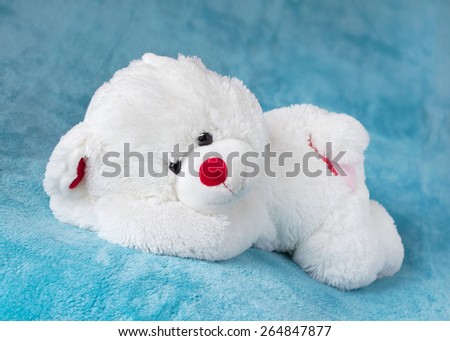 Teddy bear stuffed toy sleeping on a soft blue velvet blanket
